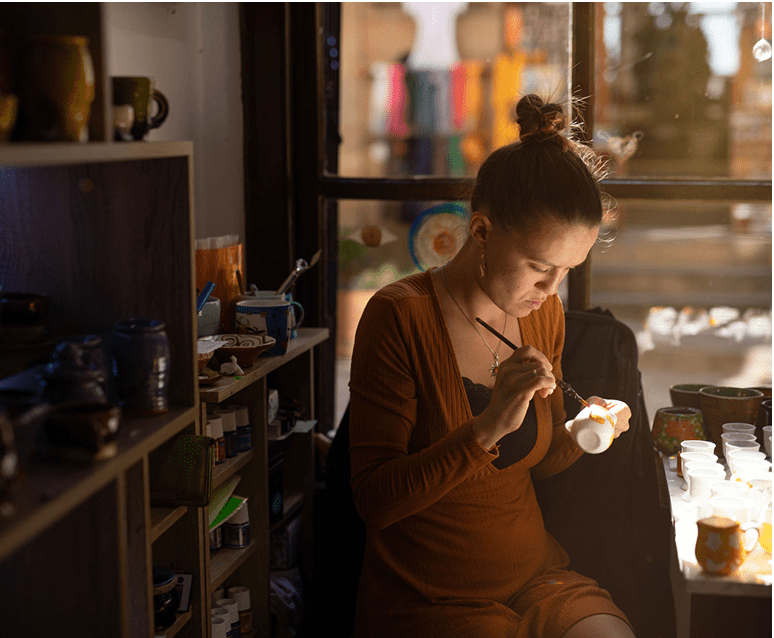 Woman painting a ceramic cup