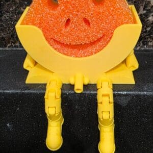 Frog-shaped sponge holder with orange sponge.